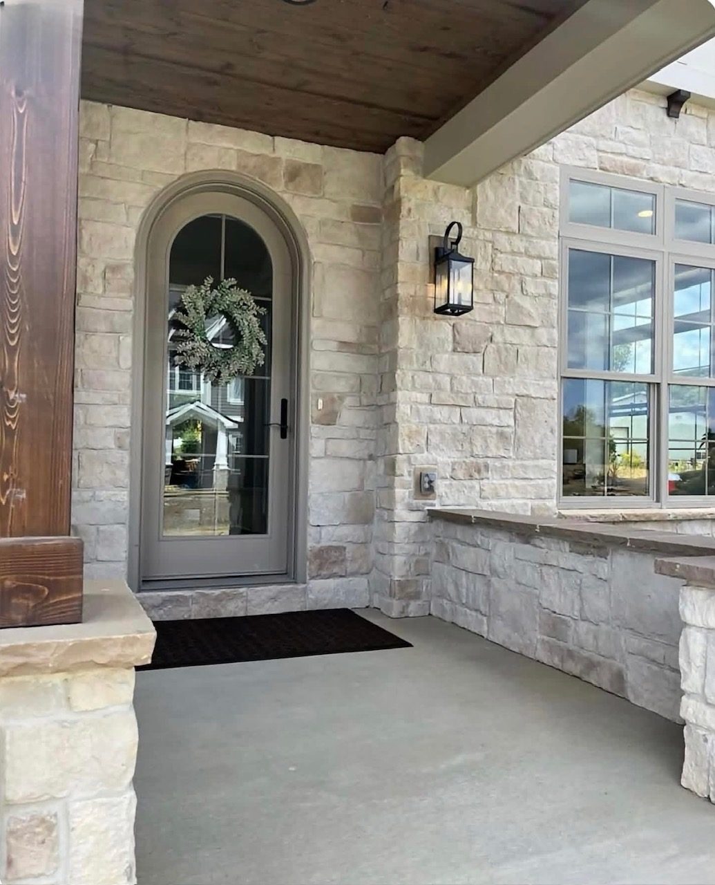 Stone-clad front porch with an arched wood door