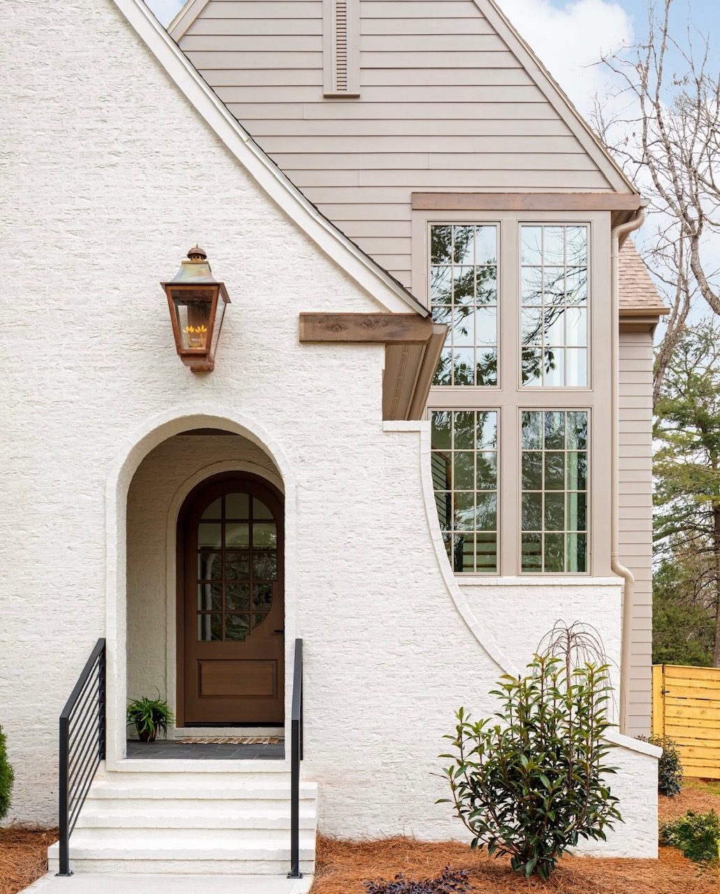 White-brick custom home with an arched entry at dusk