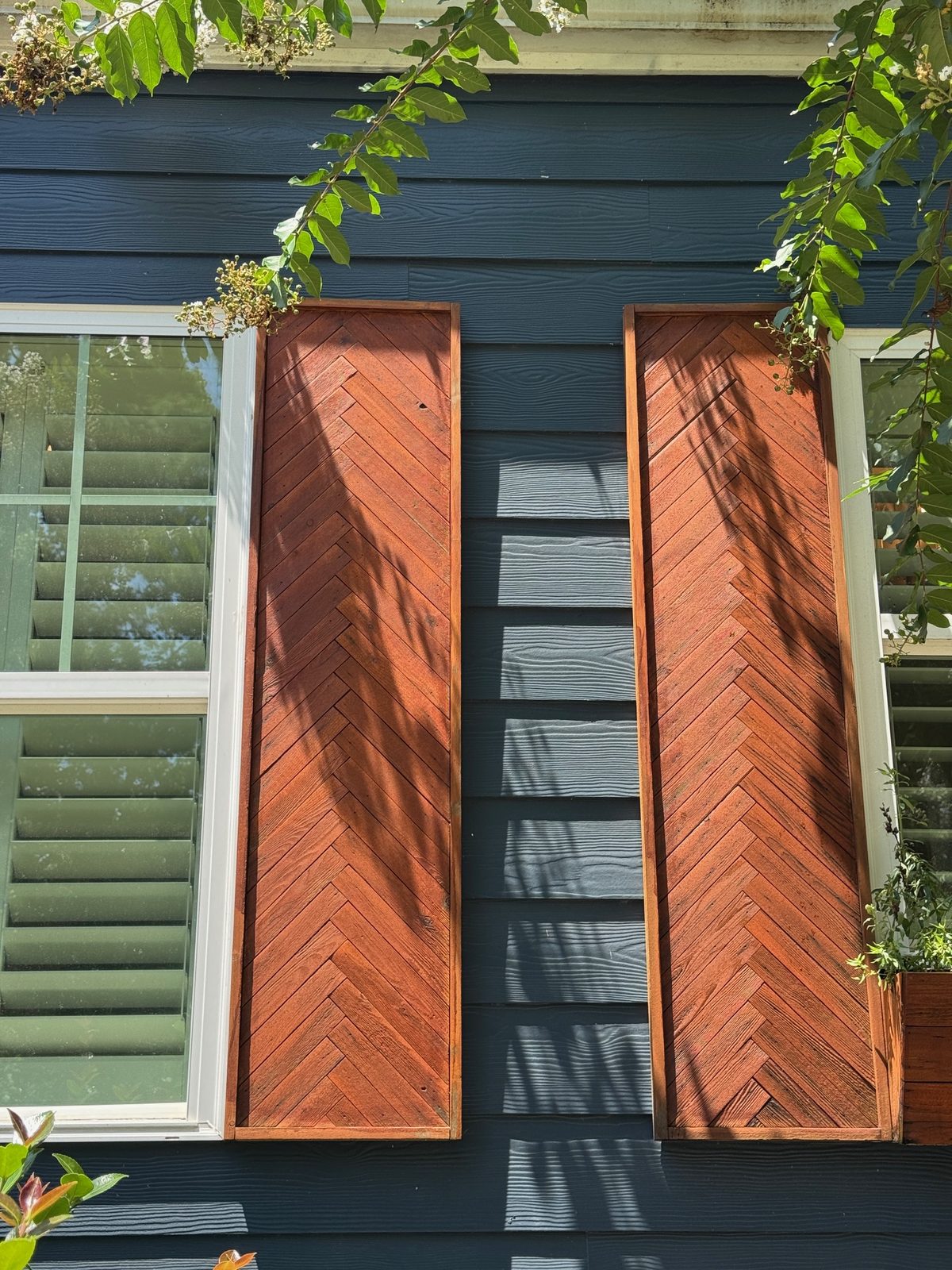 Cedar herringbone shutters and planters on navy siding