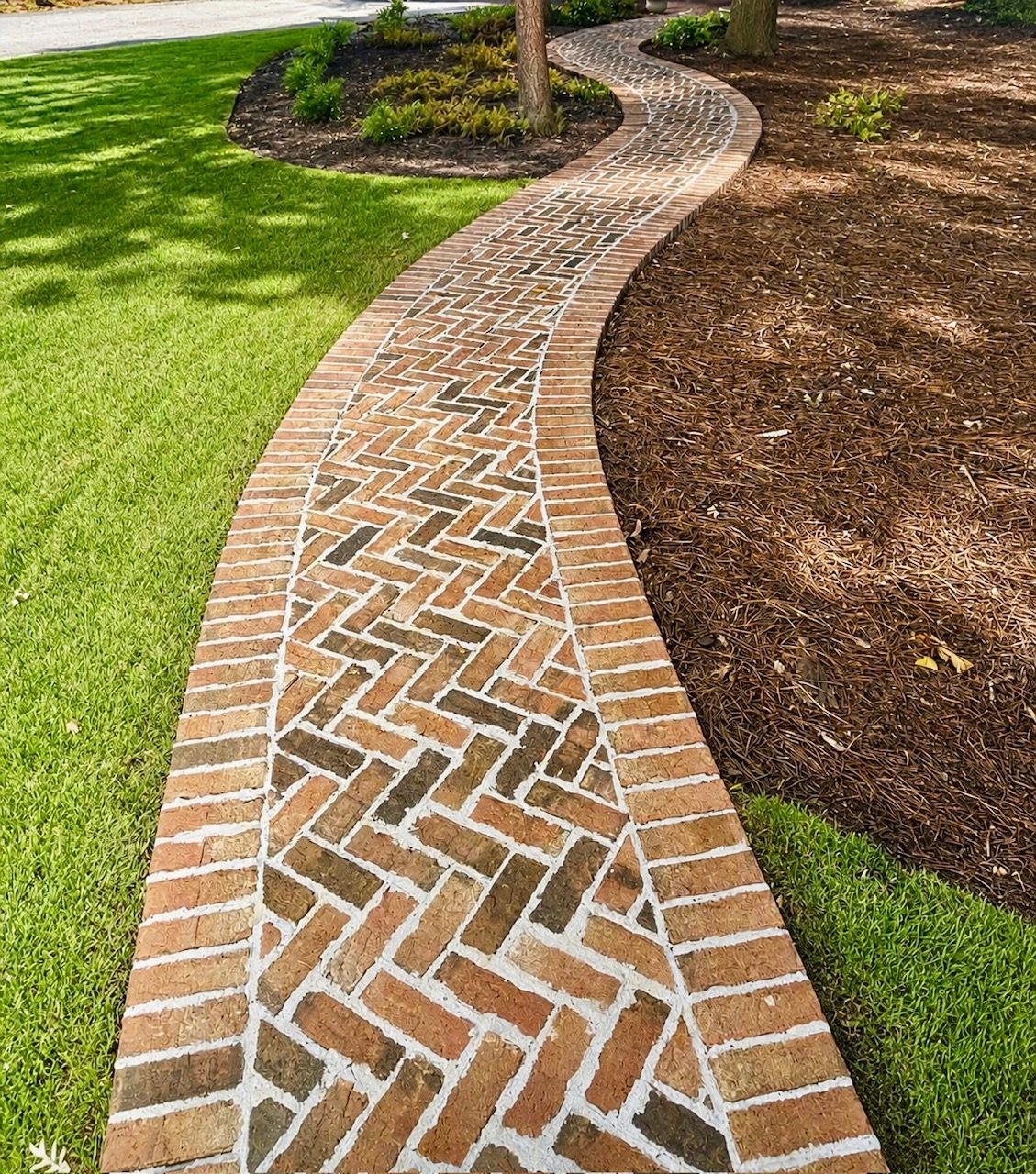 Brick herringbone walkway through a landscaped yard
